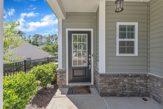 property entrance with stone siding and fence