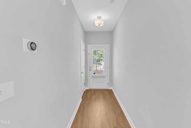 doorway with light wood-style flooring and baseboards