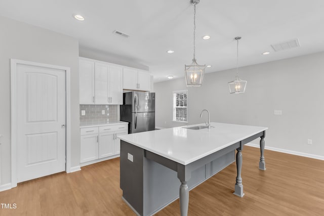 kitchen featuring freestanding refrigerator, a sink, white cabinetry, light wood-style floors, and recessed lighting