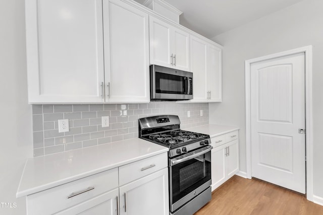 kitchen with appliances with stainless steel finishes, white cabinets, decorative backsplash, light wood-type flooring, and light countertops