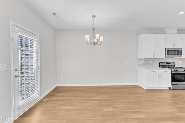 kitchen with stainless steel appliances, a chandelier, white cabinets, and light wood finished floors