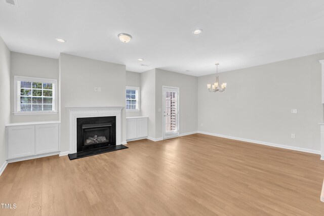unfurnished living room featuring a fireplace, a chandelier, light wood finished floors, baseboards, and recessed lighting