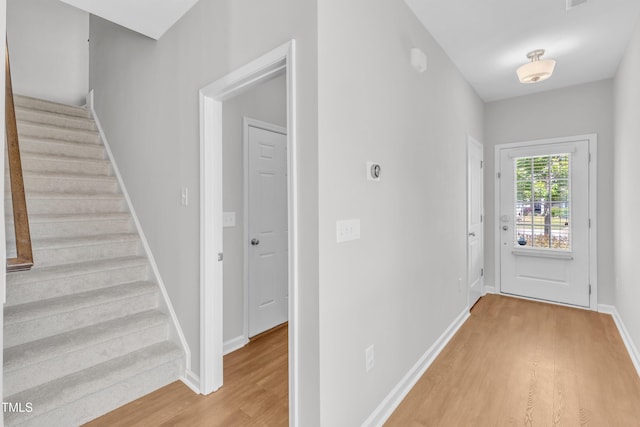 foyer entrance with light wood finished floors, stairway, and baseboards