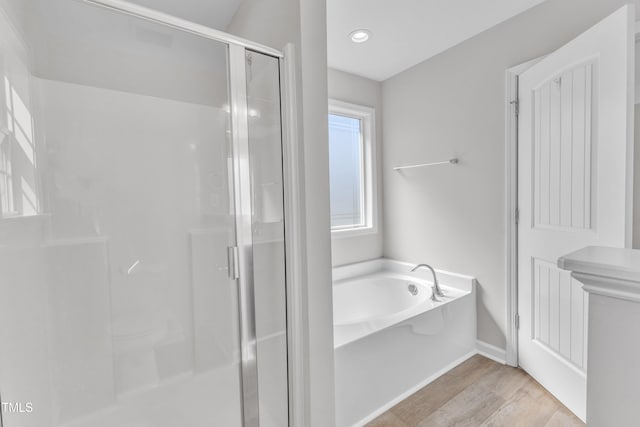 full bath featuring a stall shower, a bath, wood finished floors, baseboards, and recessed lighting