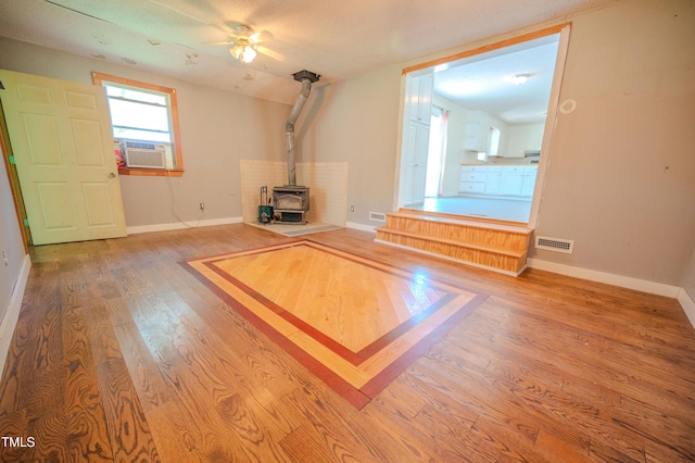 111 Marshay Meadow Rd, Youngsville, NC 27596 - unfurnished living room with a wood stove, wood finished floors, and a ceiling fan
