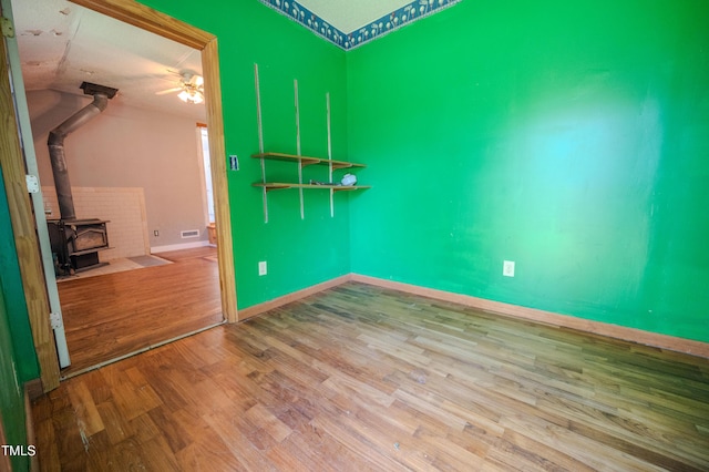 111 Marshay Meadow Rd, Youngsville, NC 27596 - empty room featuring a wood stove, wood finished floors, and ceiling fan