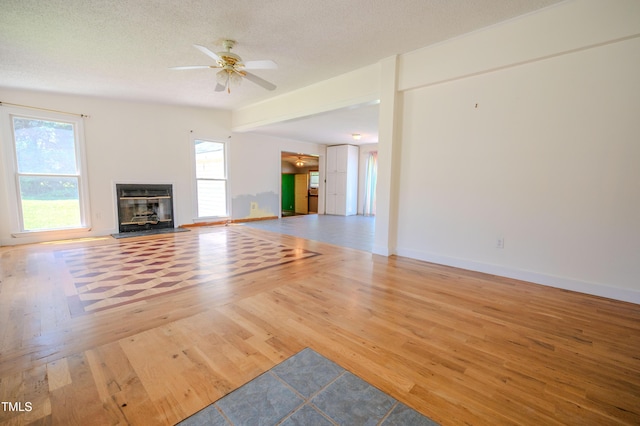 111 Marshay Meadow Rd, Youngsville, NC 27596 - unfurnished living room featuring wood finished floors, a ceiling fan, a glass covered fireplace, and a textured ceiling