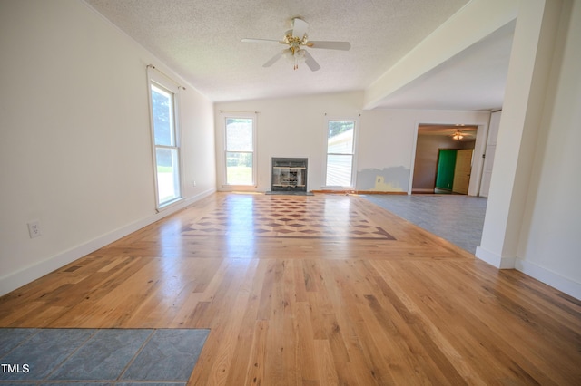 111 Marshay Meadow Rd, Youngsville, NC 27596 - unfurnished living room featuring ceiling fan, healthy amount of natural light, a textured ceiling, lofted ceiling, and a glass covered fireplace