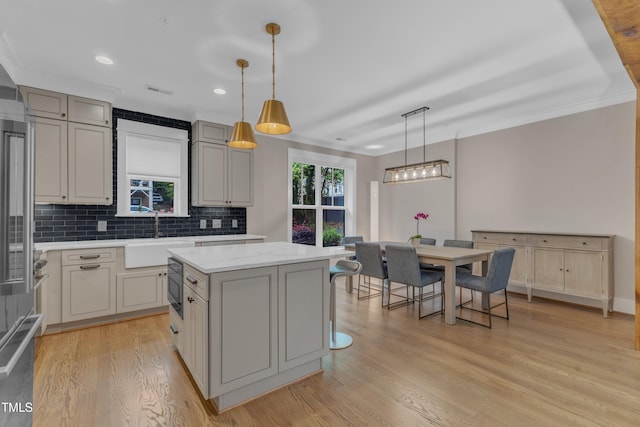 kitchen with a sink, ornamental molding, a kitchen island, backsplash, and gray cabinets