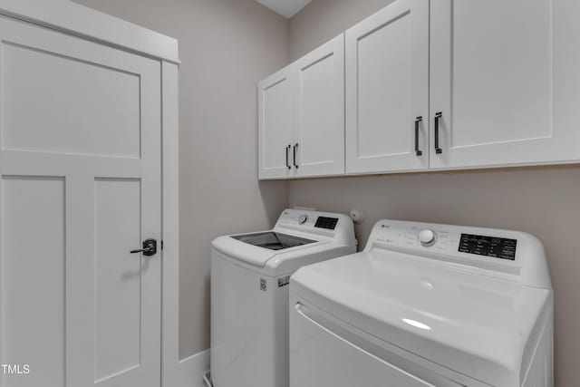 clothes washing area featuring washer and dryer and cabinet space