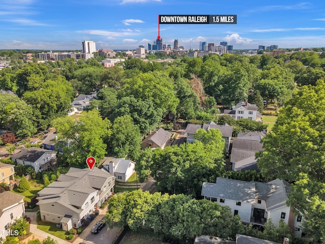aerial view of property and surrounding area featuring nearby suburban area, a tree filled landscape, and nearby urban area