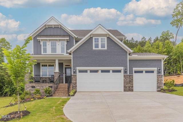 craftsman-style home with covered porch, an attached garage, stone siding, driveway, and a front yard