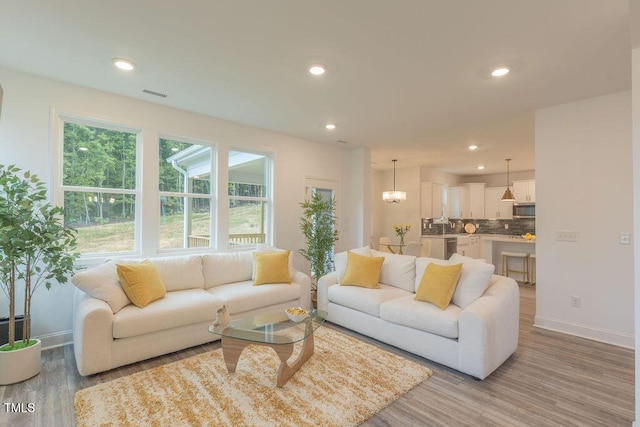 living area with light wood-type flooring, visible vents, baseboards, and recessed lighting