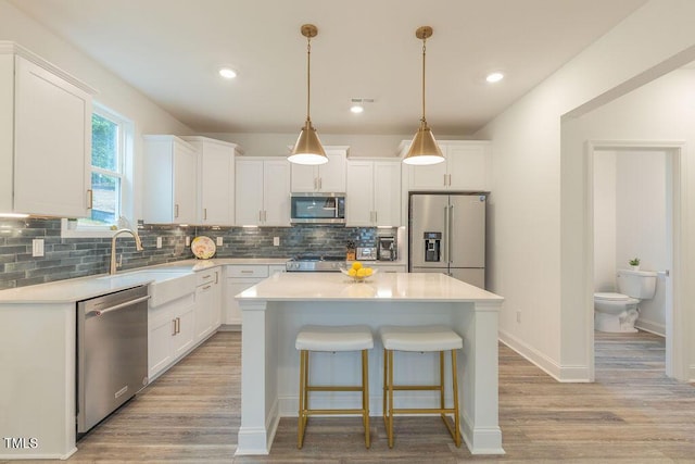 kitchen with light countertops, appliances with stainless steel finishes, a kitchen island, and white cabinetry