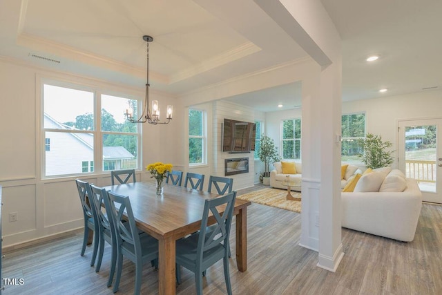 dining space featuring ornamental molding, a decorative wall, visible vents, and wood finished floors