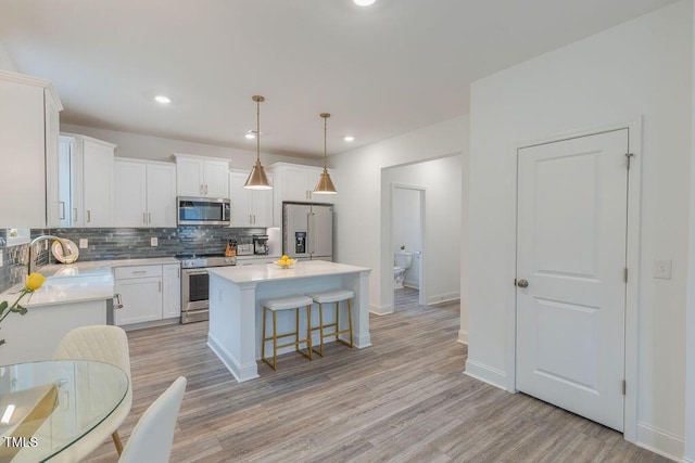 kitchen featuring stainless steel appliances, a sink, decorative backsplash, a kitchen island, and light countertops
