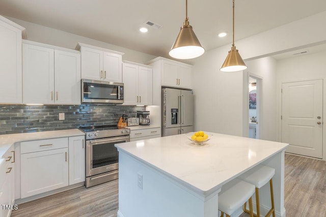 kitchen featuring light wood finished floors, stainless steel appliances, backsplash, and white cabinets