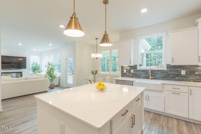 kitchen featuring a sink, dishwasher, white cabinetry, light countertops, and light wood-style floors