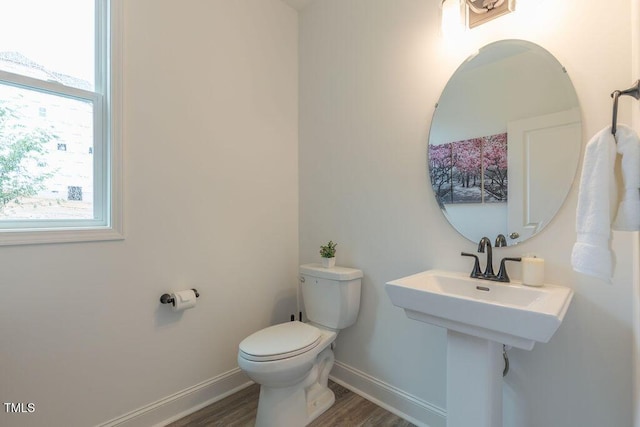 bathroom with baseboards, toilet, plenty of natural light, and wood finished floors