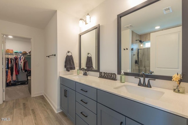 full bath with a stall shower, a spacious closet, double vanity, and a sink