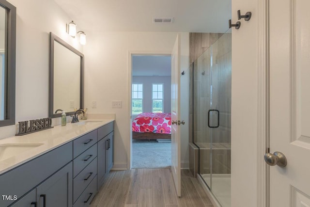bathroom featuring a stall shower, connected bathroom, a sink, and wood finished floors