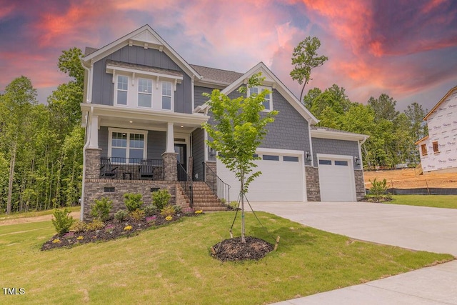 craftsman-style house featuring concrete driveway, stone siding, covered porch, and board and batten siding