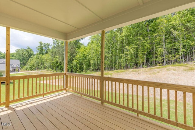 wooden deck with a forest view and a lawn