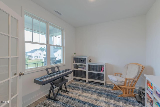 living area with baseboards, visible vents, and wood finished floors