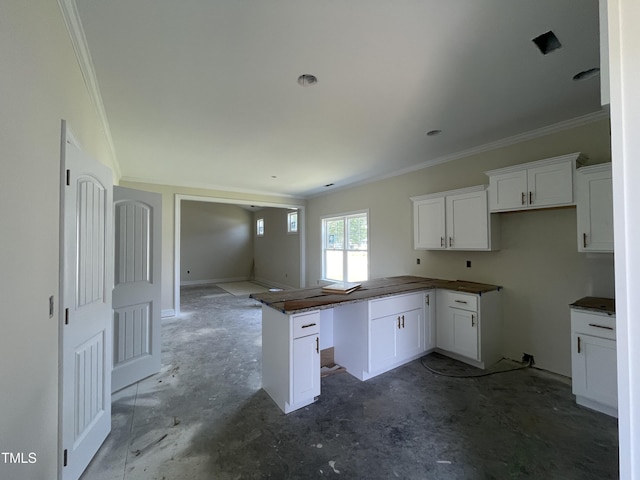 506 S Vance St, Fremont, NC 27830 - kitchen with ornamental molding, white cabinetry, dark countertops, a peninsula, and unfinished concrete floors
