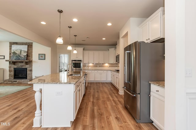 3536 Greenville Loop Rd, Wake Forest, NC 27587 - kitchen featuring stainless steel appliances, a sink, a stone fireplace, open floor plan, and light stone countertops