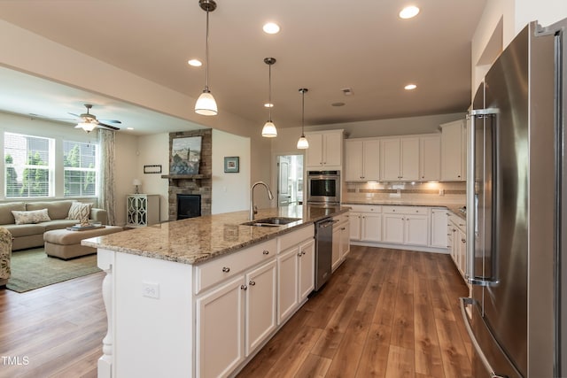 3536 Greenville Loop Rd, Wake Forest, NC 27587 - kitchen featuring appliances with stainless steel finishes, a sink, open floor plan, a stone fireplace, and wood finished floors