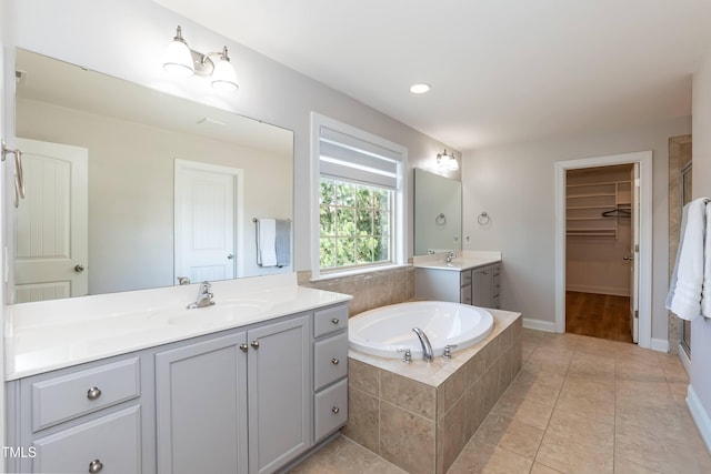 3536 Greenville Loop Rd, Wake Forest, NC 27587 - bathroom featuring two vanities, a bath, a walk in closet, baseboards, and tile patterned floors