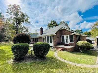rear view of property with a yard, brick siding, and a chimney