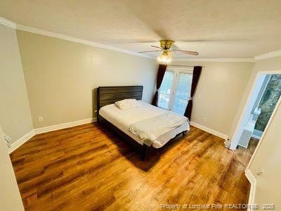 bedroom featuring baseboards, multiple windows, ornamental molding, and wood finished floors