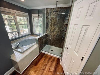 full bathroom with a marble finish shower, a jetted tub, crown molding, and wood finished floors
