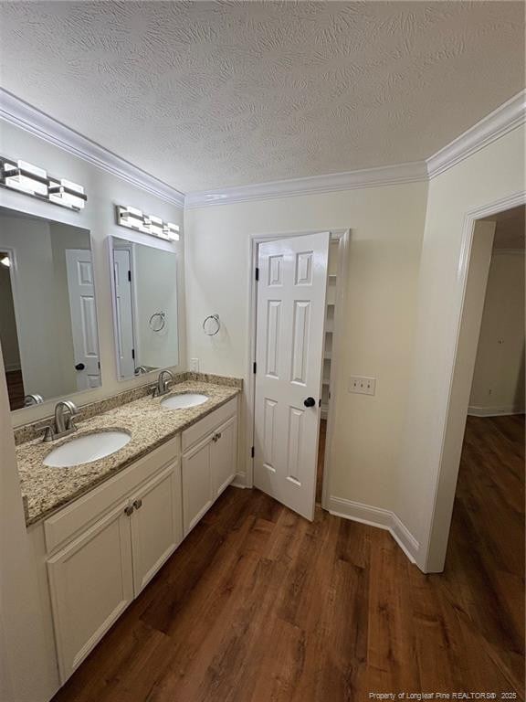 6976 Kings Lynn Loop, Fayetteville, NC 28304 - full bathroom featuring crown molding, wood finished floors, double vanity, a textured ceiling, and baseboards