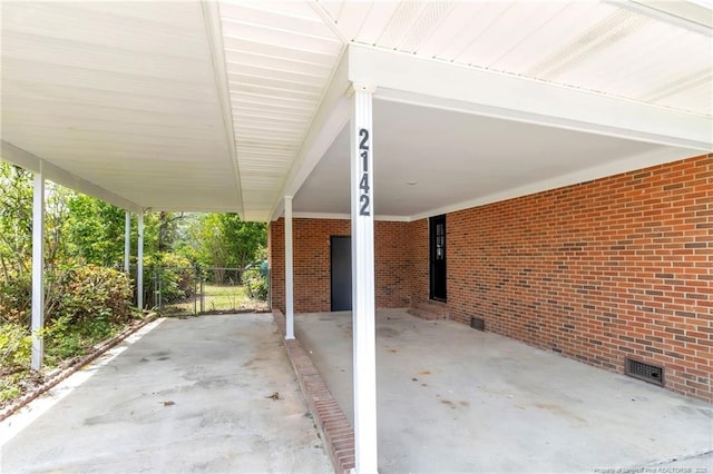 view of patio / terrace featuring fence, a carport, and visible vents
