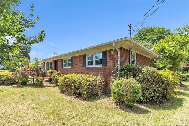 view of side of property featuring brick siding and a lawn