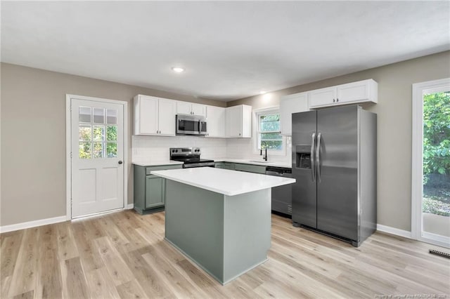 kitchen with light wood finished floors, light countertops, a center island, and appliances with stainless steel finishes