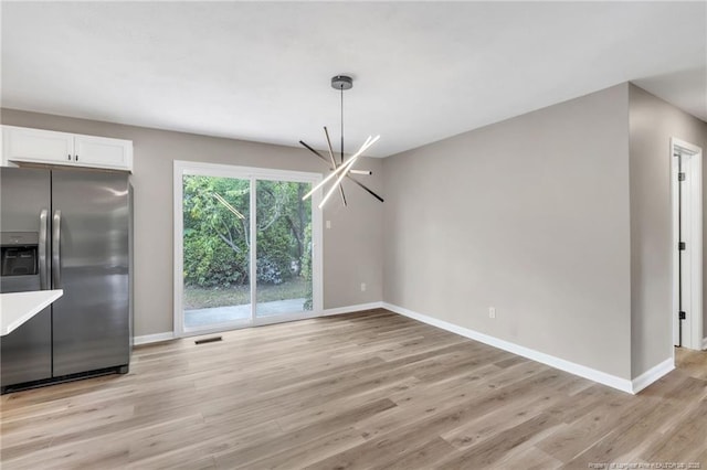 unfurnished dining area with a notable chandelier, baseboards, and light wood-style floors