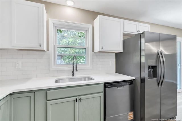 kitchen with a sink, tasteful backsplash, light countertops, and appliances with stainless steel finishes