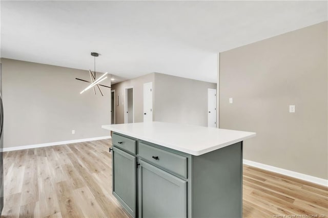 kitchen featuring baseboards, light countertops, hanging light fixtures, a kitchen island, and light wood-style floors