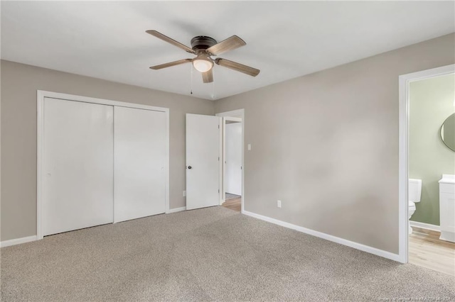 unfurnished bedroom with a closet, baseboards, ensuite bathroom, carpet flooring, and ceiling fan