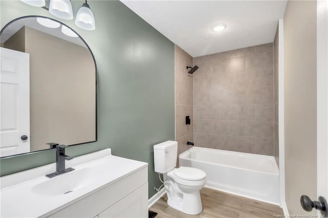 bathroom featuring toilet, wood finished floors, shower / bath combination, baseboards, and vanity