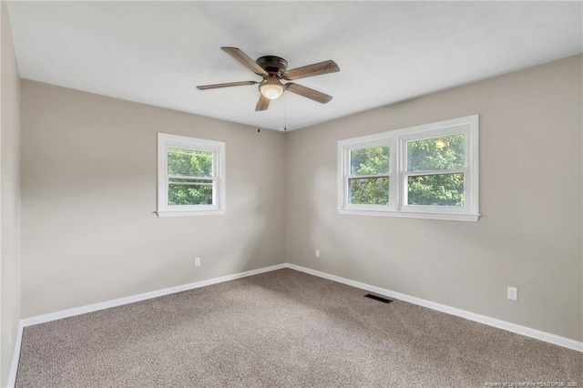 carpeted spare room featuring ceiling fan, baseboards, and visible vents
