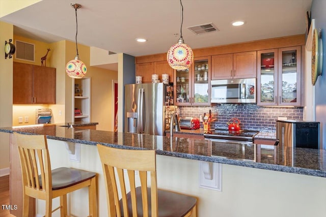 kitchen featuring stainless steel appliances, brown cabinets, a breakfast bar area, decorative backsplash, and pendant lighting