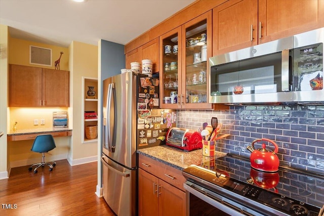 kitchen featuring stainless steel appliances, backsplash, dark wood-style floors, and brown cabinetry