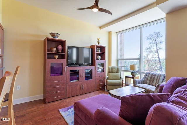 living room featuring wood finished floors, a ceiling fan, and baseboards