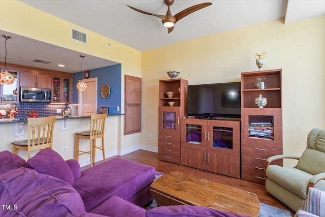 living room with dark wood finished floors, a ceiling fan, and baseboards