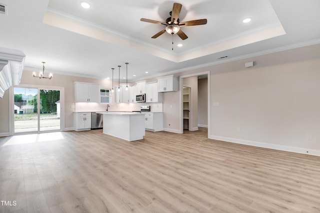 157 Gumtop Dr, Zebulon, NC 27597 - unfurnished living room with a raised ceiling, a chandelier, light wood finished floors, ceiling fan, and crown molding